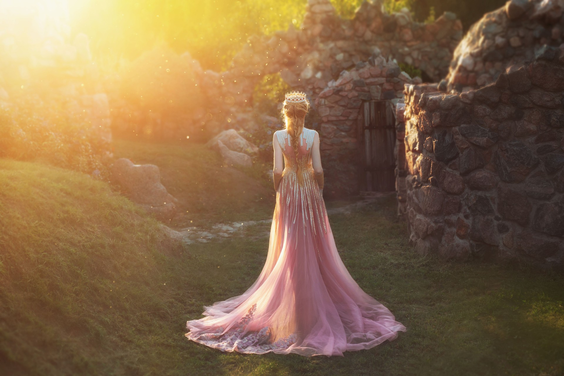 Shooting without a face, from the back. Wonderful princess with blond hair and a crown. is wearing an amazing light pink dress with gold ornaments and a long train. Queen walks in the garden in the rays of sun